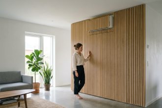 Climatisation murale dissimulée derrière un panneau en bois de chêne dans un salon moderne au style scandinave