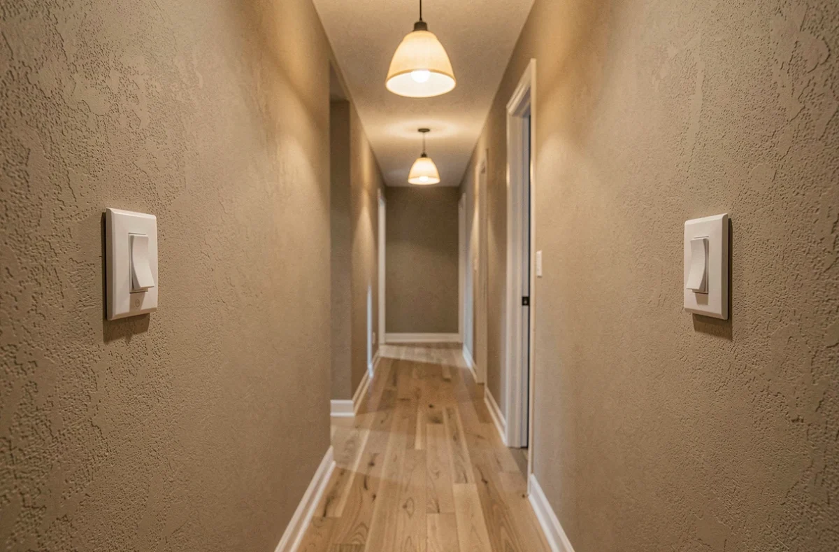 Couloir résidentiel avec deux interrupteurs va-et-vient installés aux deux extrémités et deux lampes au plafond allumées